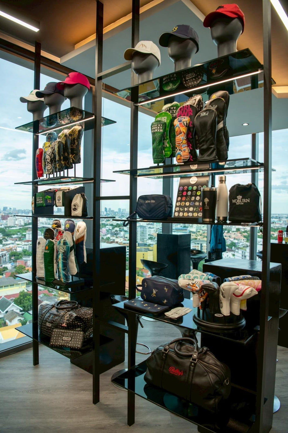 Display case with various items including hats and bags in an indoor setting with a cityscape view.