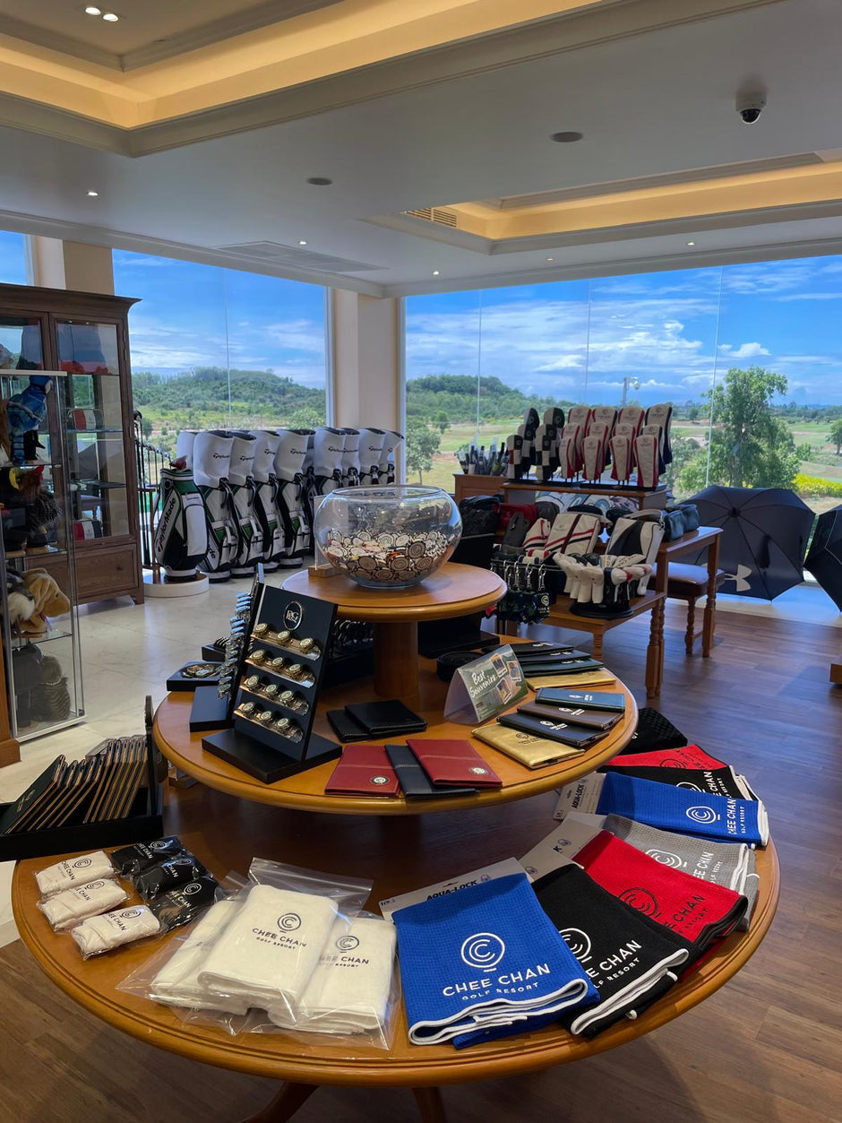 Display of golf accessories in a store with large windows showing an outdoor view.